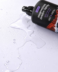 Salt + Earth Co. Magnesium Dream Spray laying on purple bench top with dream spray spilt on the bench
